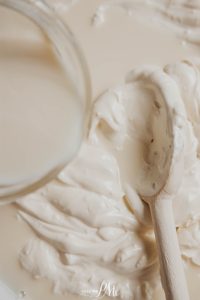 Whipped cream on a white plate with a wooden spoon.