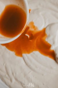 A sauce being poured into a bowl of ice cream.