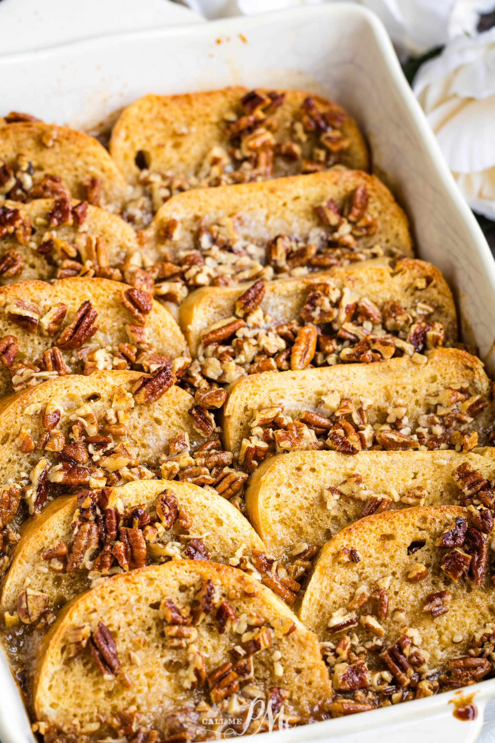 A white baking dish filled with french toast and pecans.