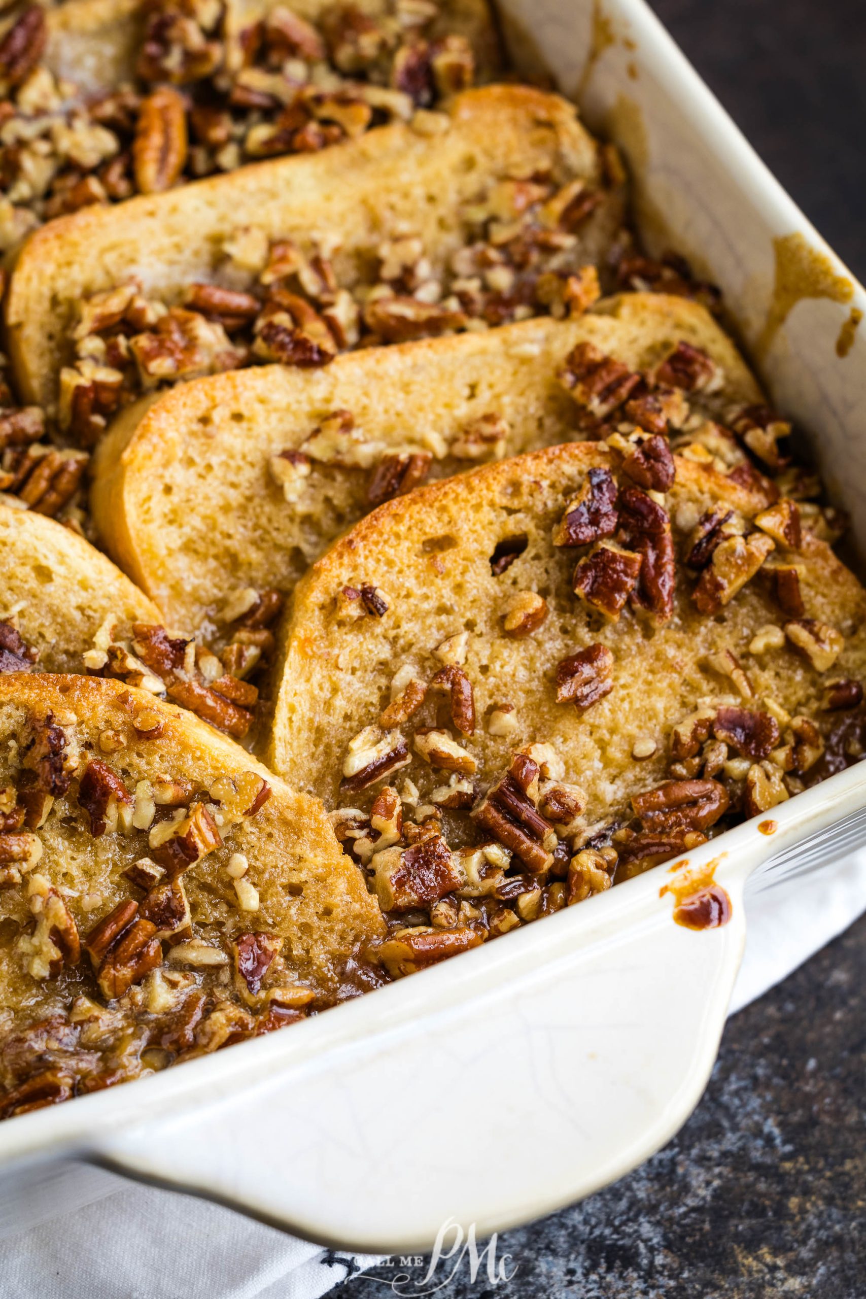 French toast casserole with pecans in a white baking dish.