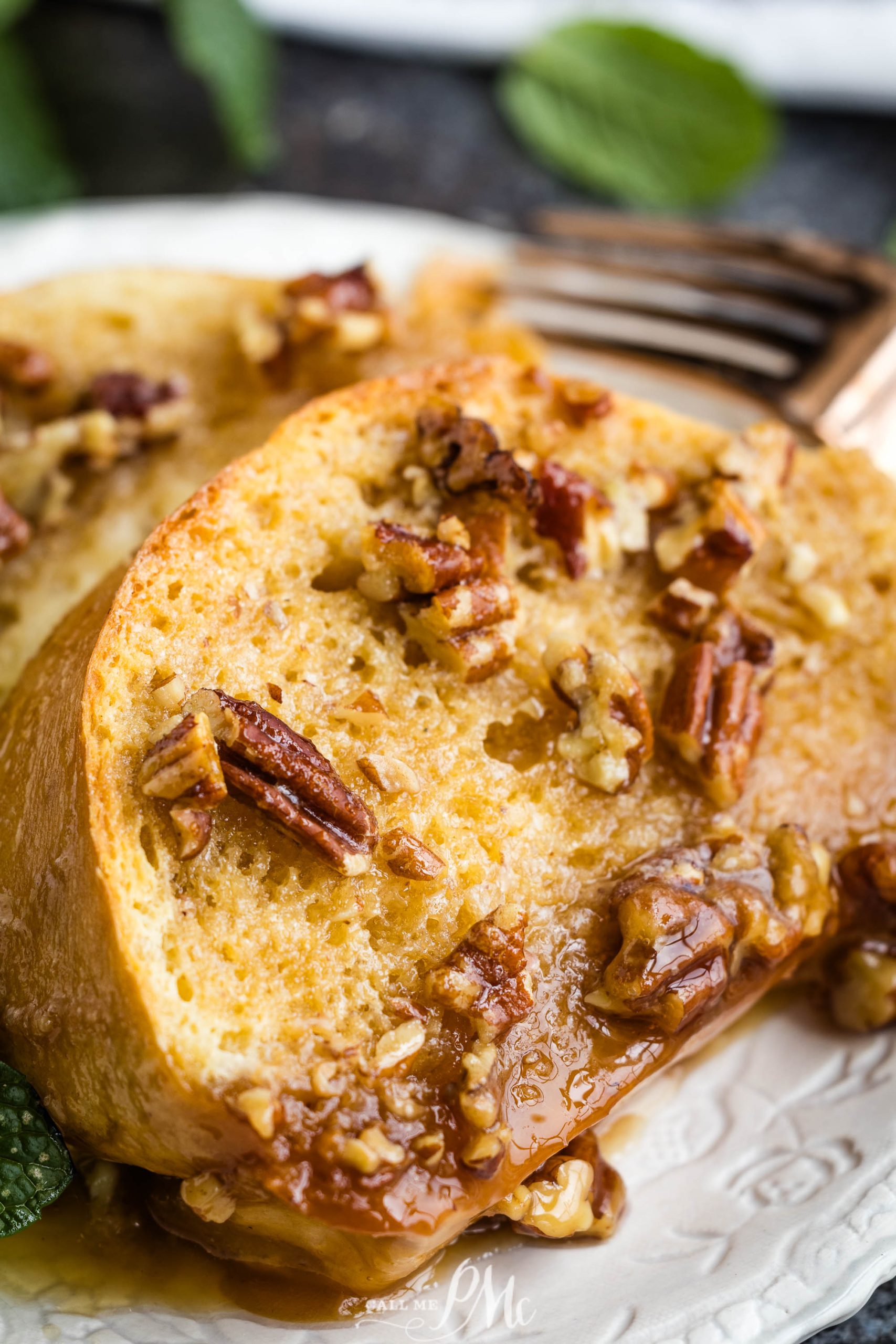 A slice of bread with caramel sauce and pecans on a plate.