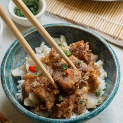 A bowl of food with chopsticks.