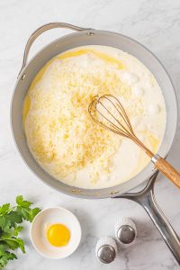 A frying pan with eggs and parmesan cheese.