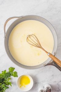 A pan with ingredients and a whisk.