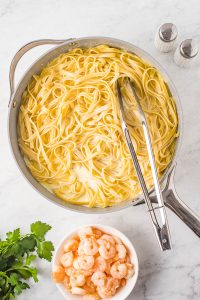 A pan with pasta and shrimp in it.