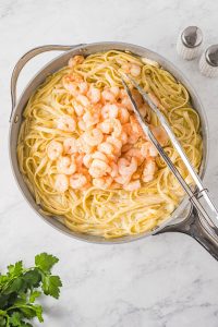 Shrimp and pasta in a pan on a marble countertop.