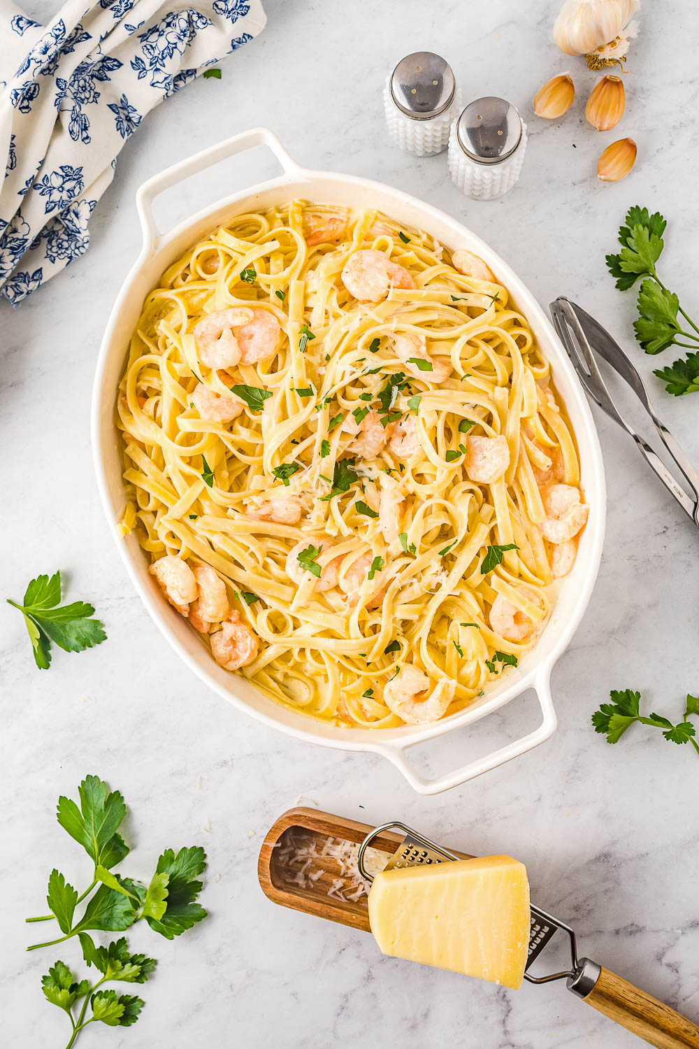 A dish of pasta with shrimp and parsley.