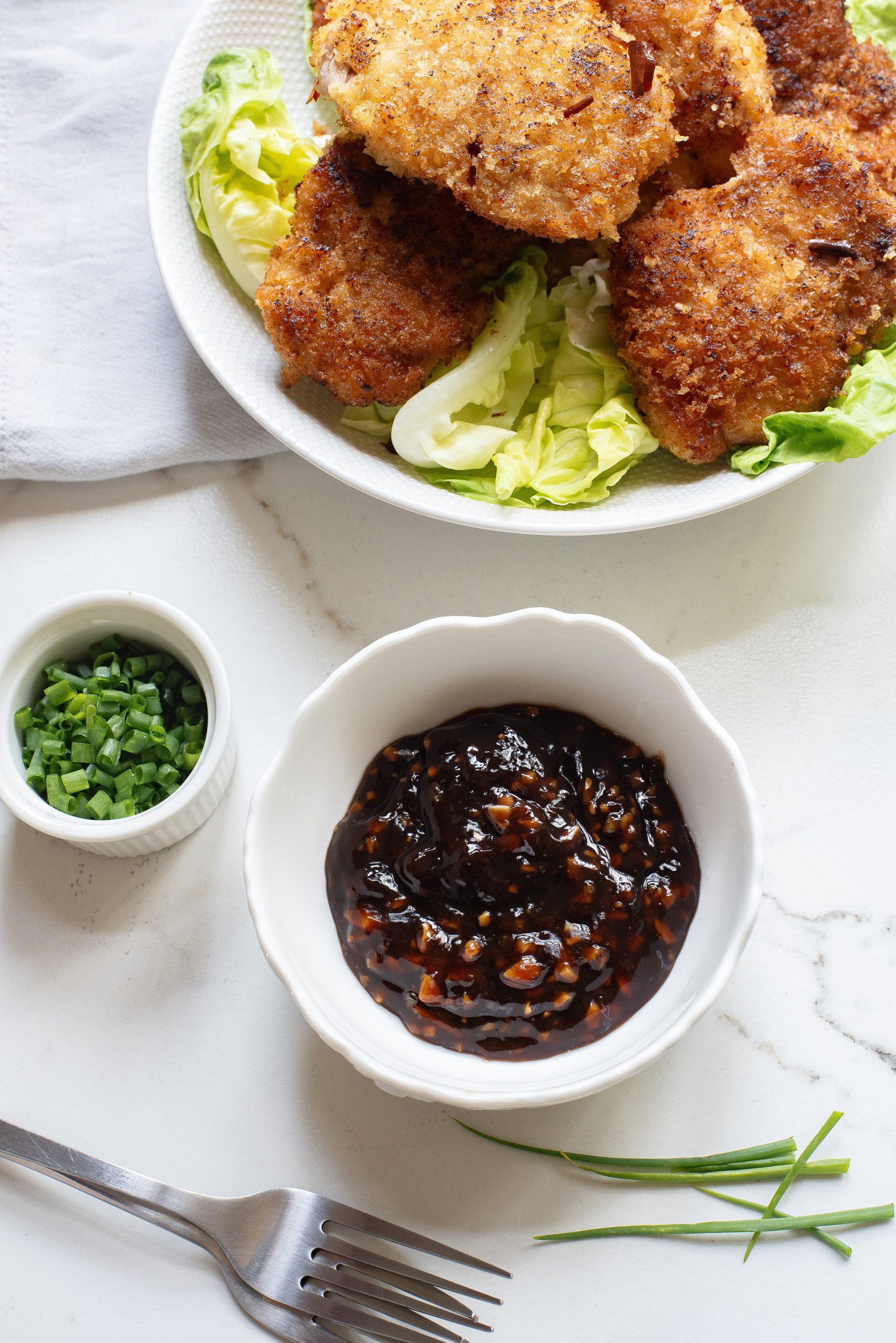 A white plate with fried chicken and a bowl of dipping sauce.