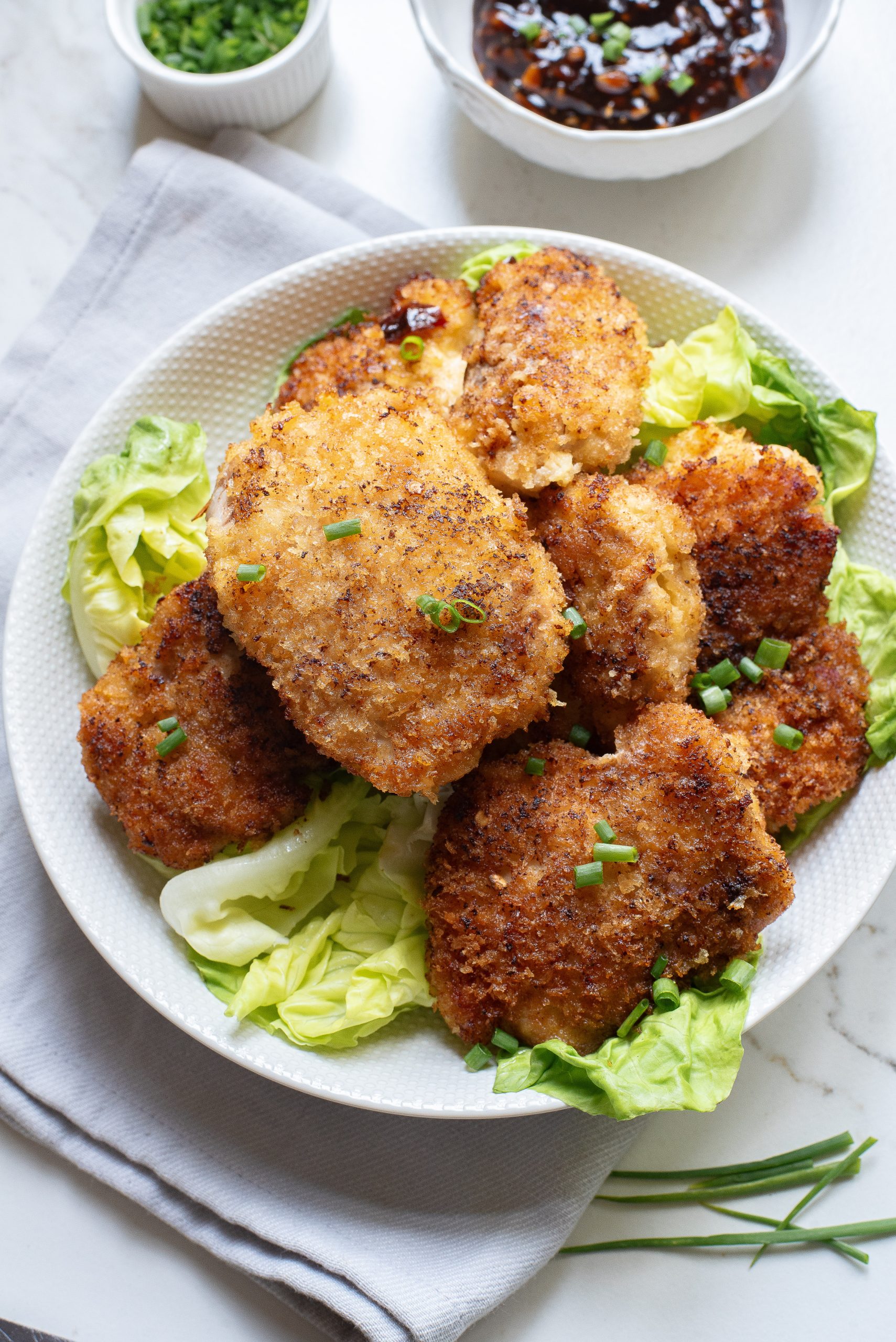 Fried chicken with asian dipping sauce on a white plate.