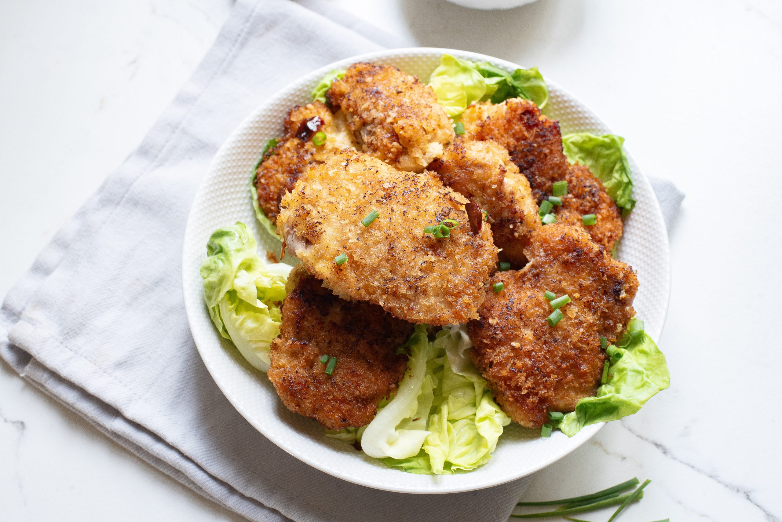 Chicken nuggets on a white plate with lettuce.