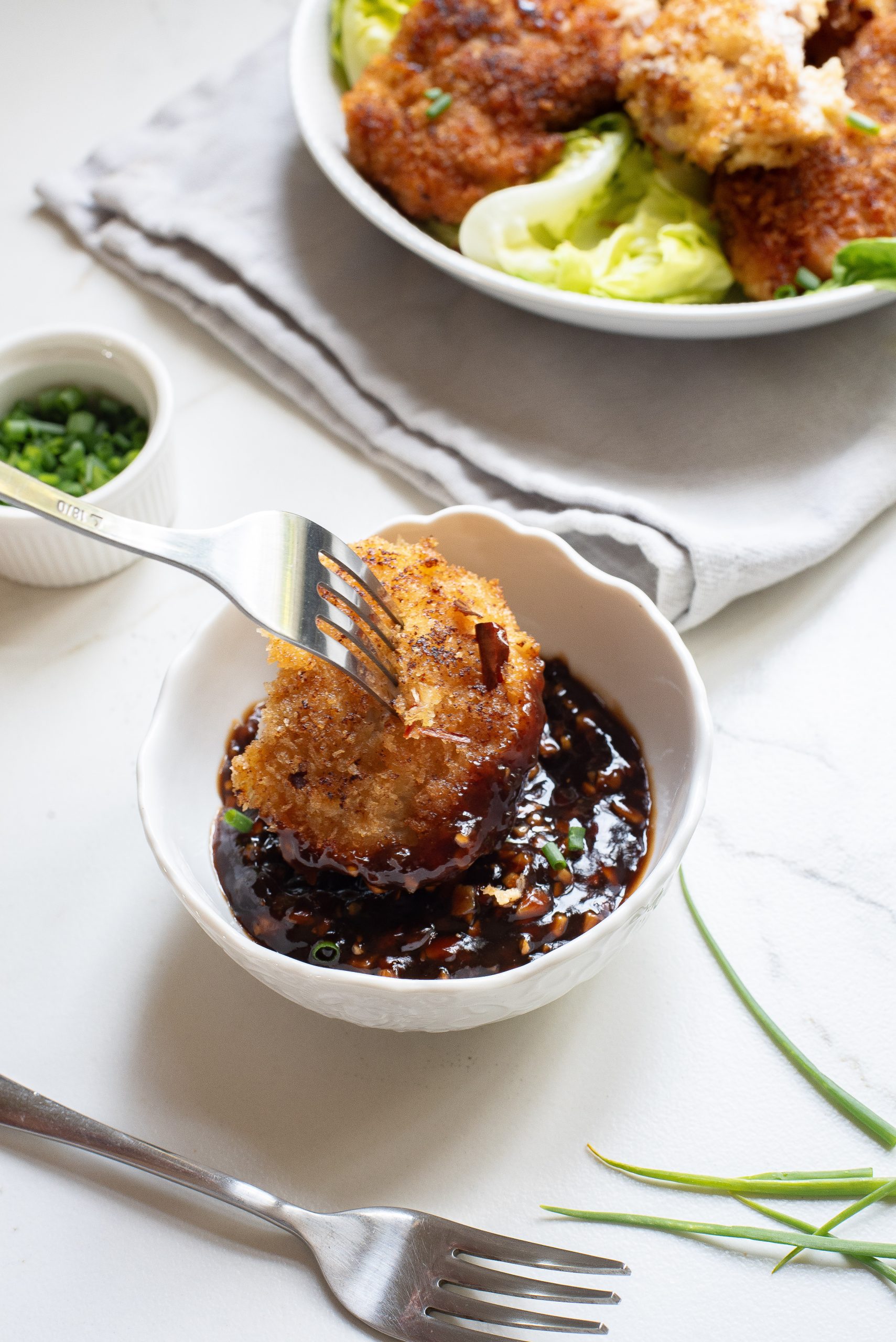 A white plate with a fork and a bowl of chicken.