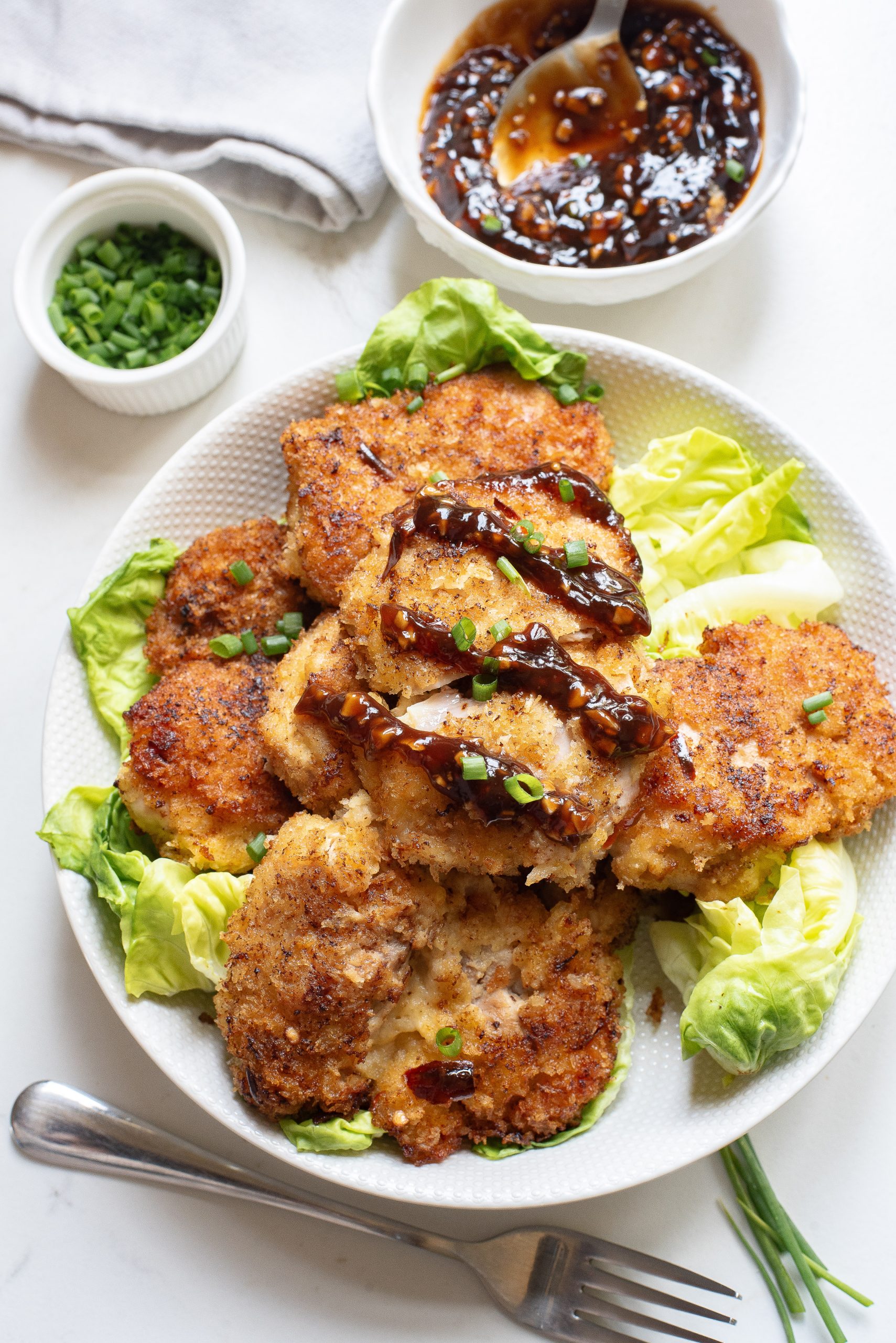 A white plate with chicken patties and lettuce on it.