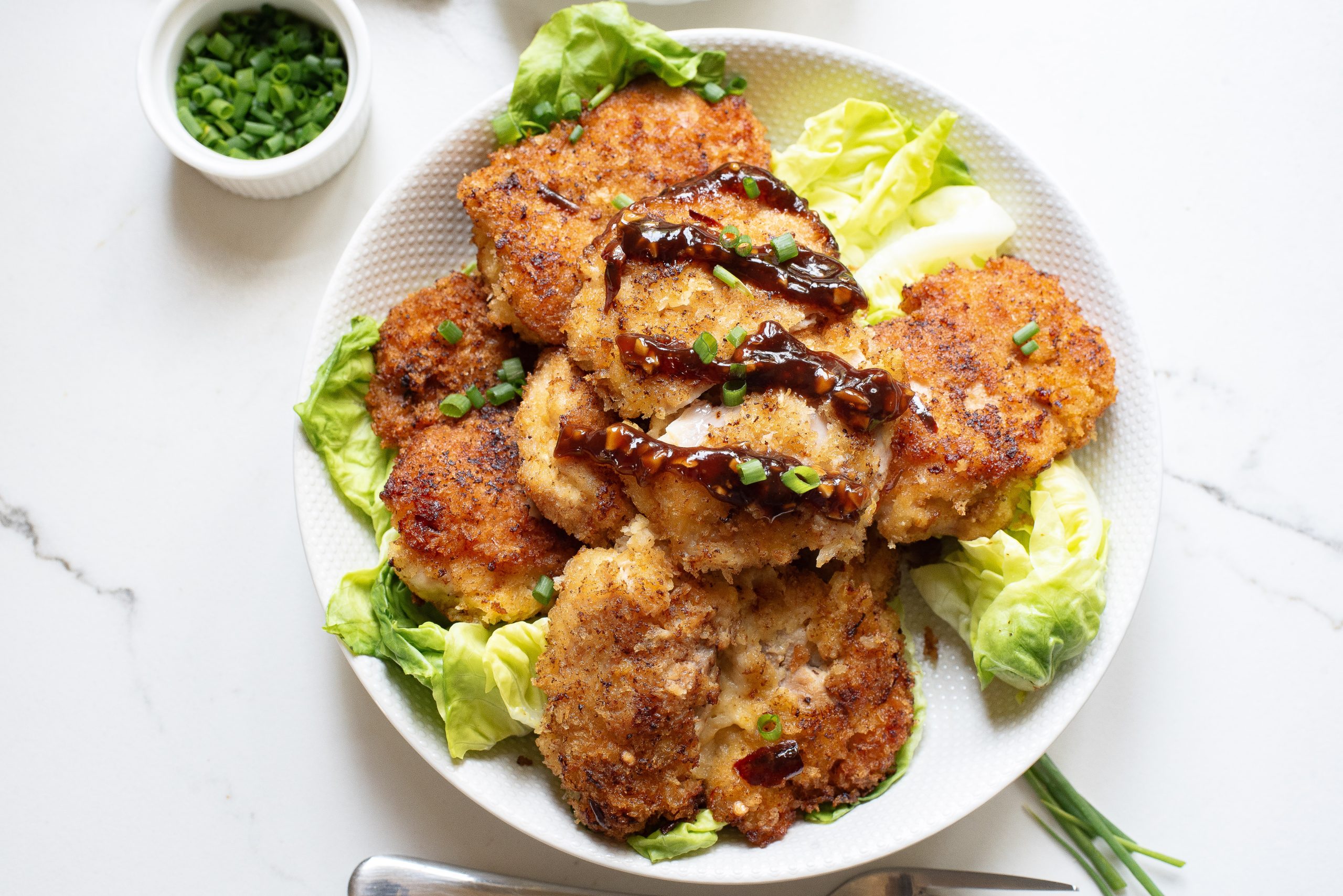 A white plate with chicken and lettuce.