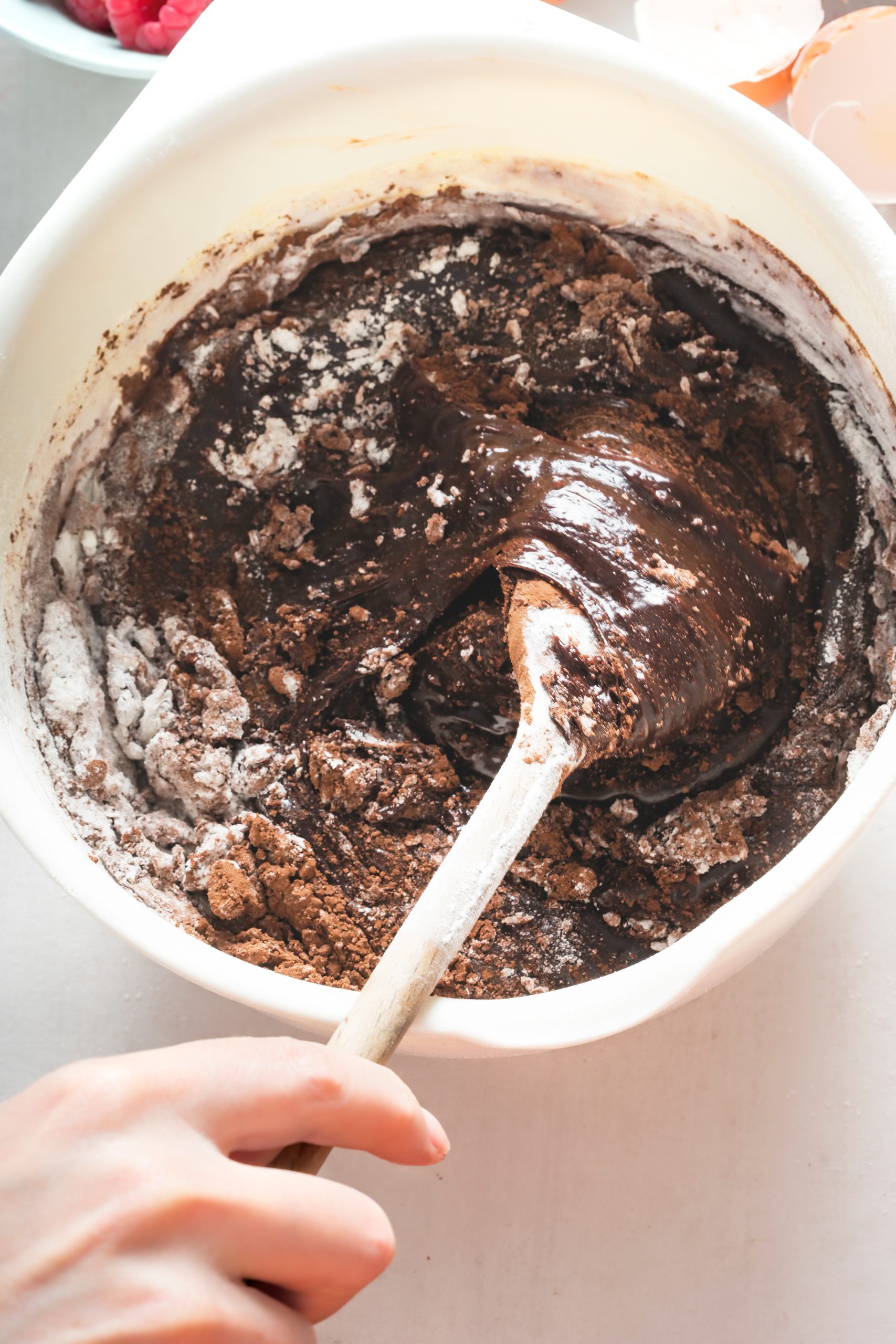 A person mixing chocolate batter in a bowl.