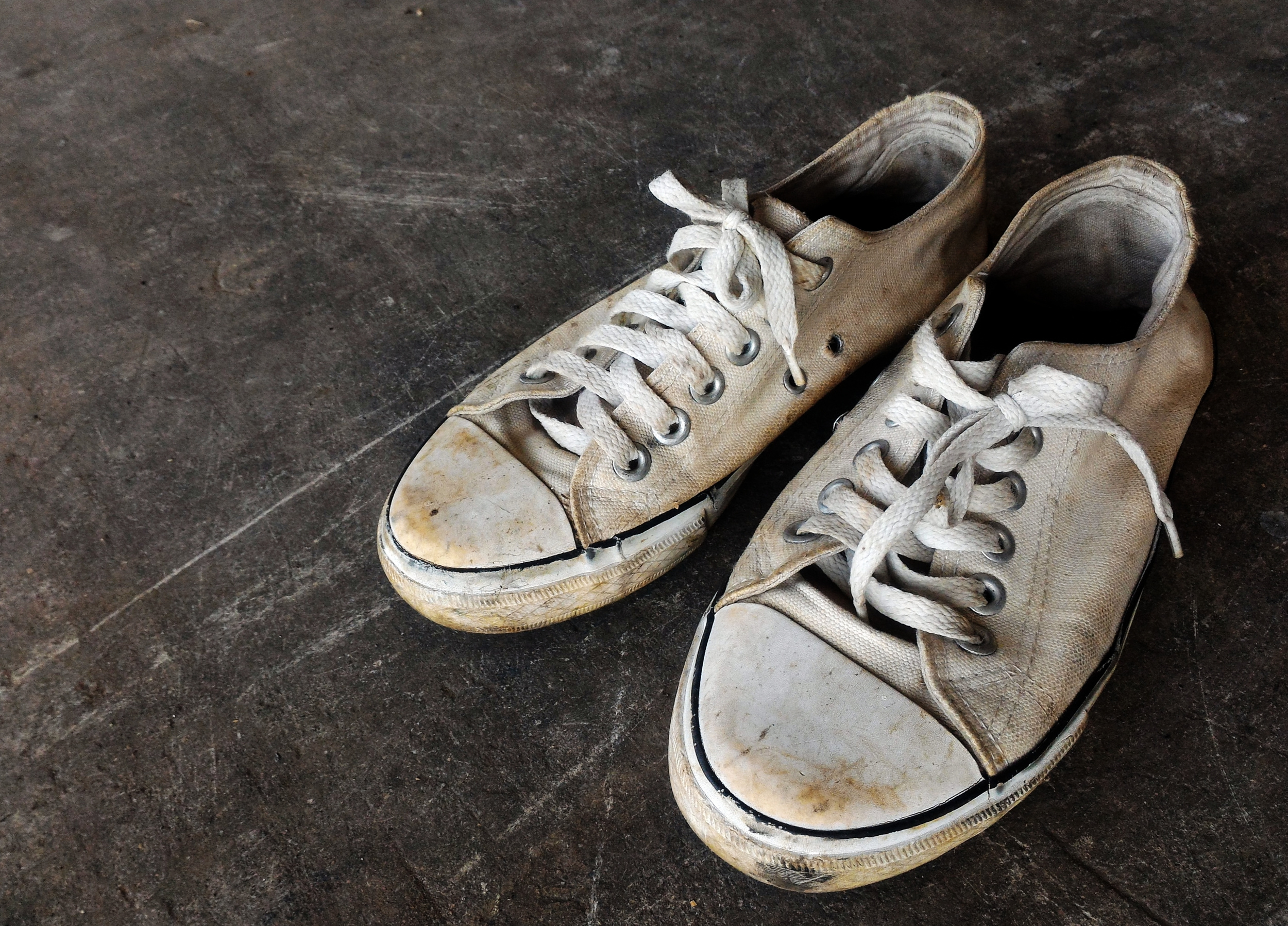 A pair of white sneakers on a concrete floor.