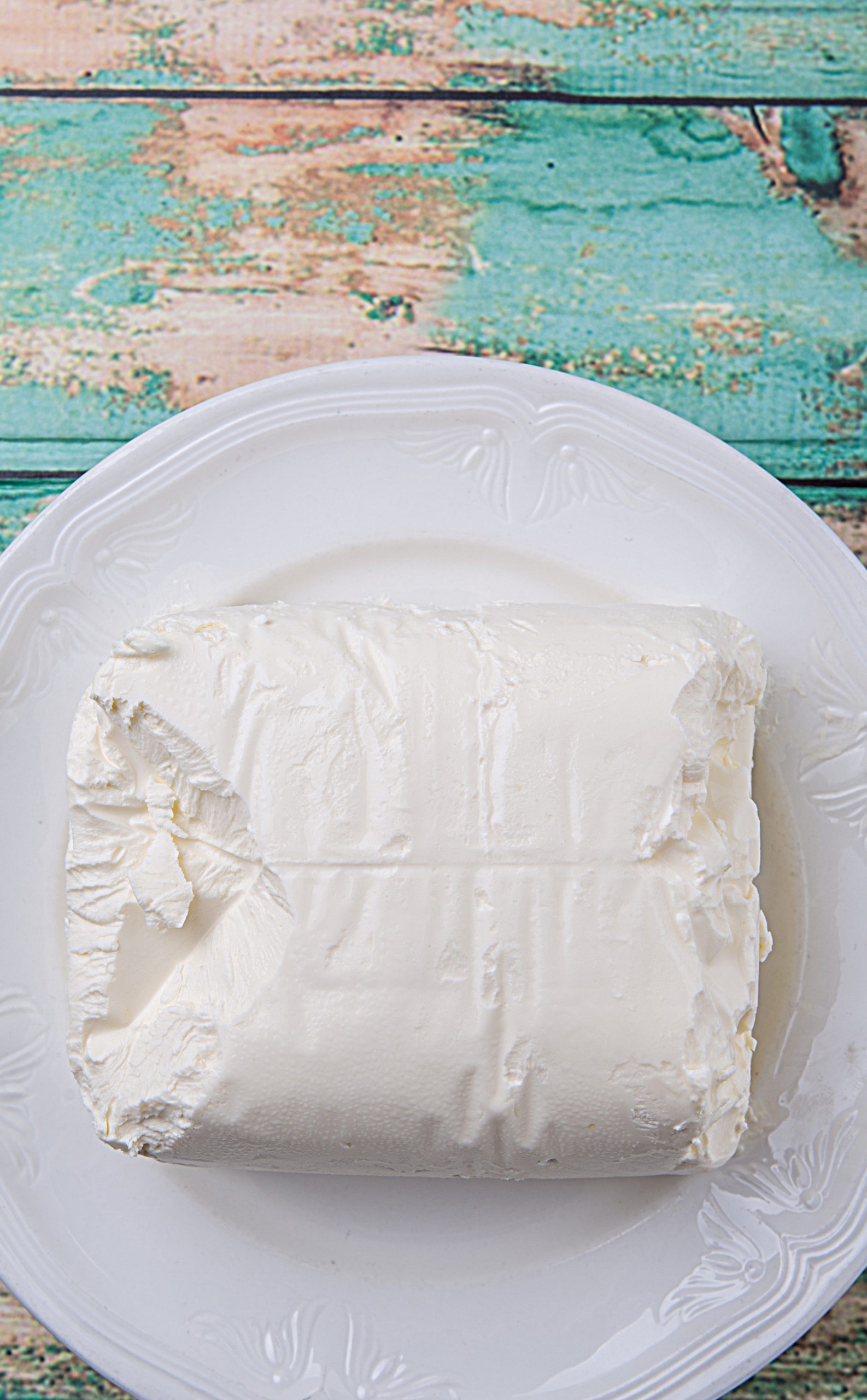 A white plate on a wooden table with cream cheese.
