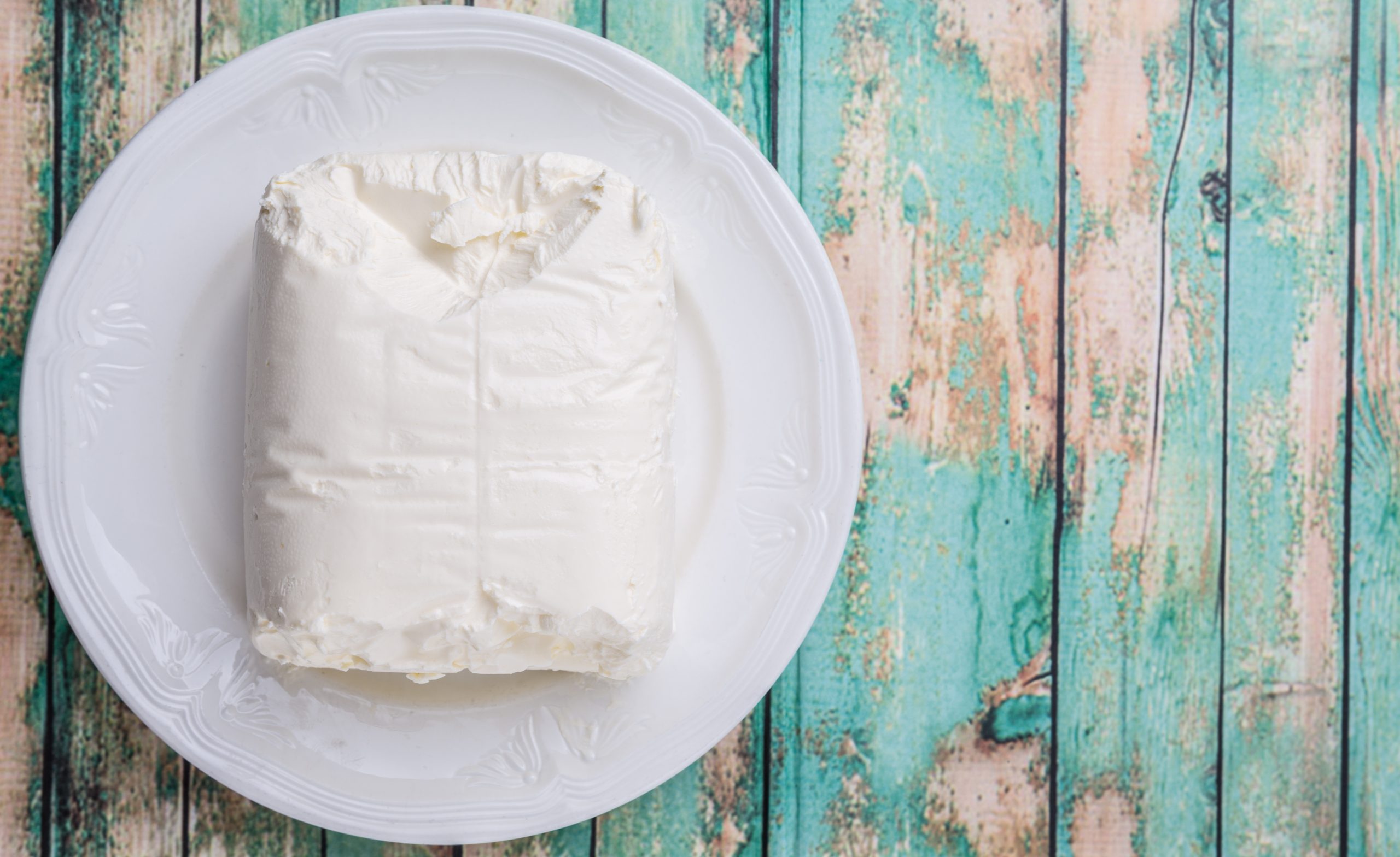 A piece of cheese wrapped in plastic on a plate.