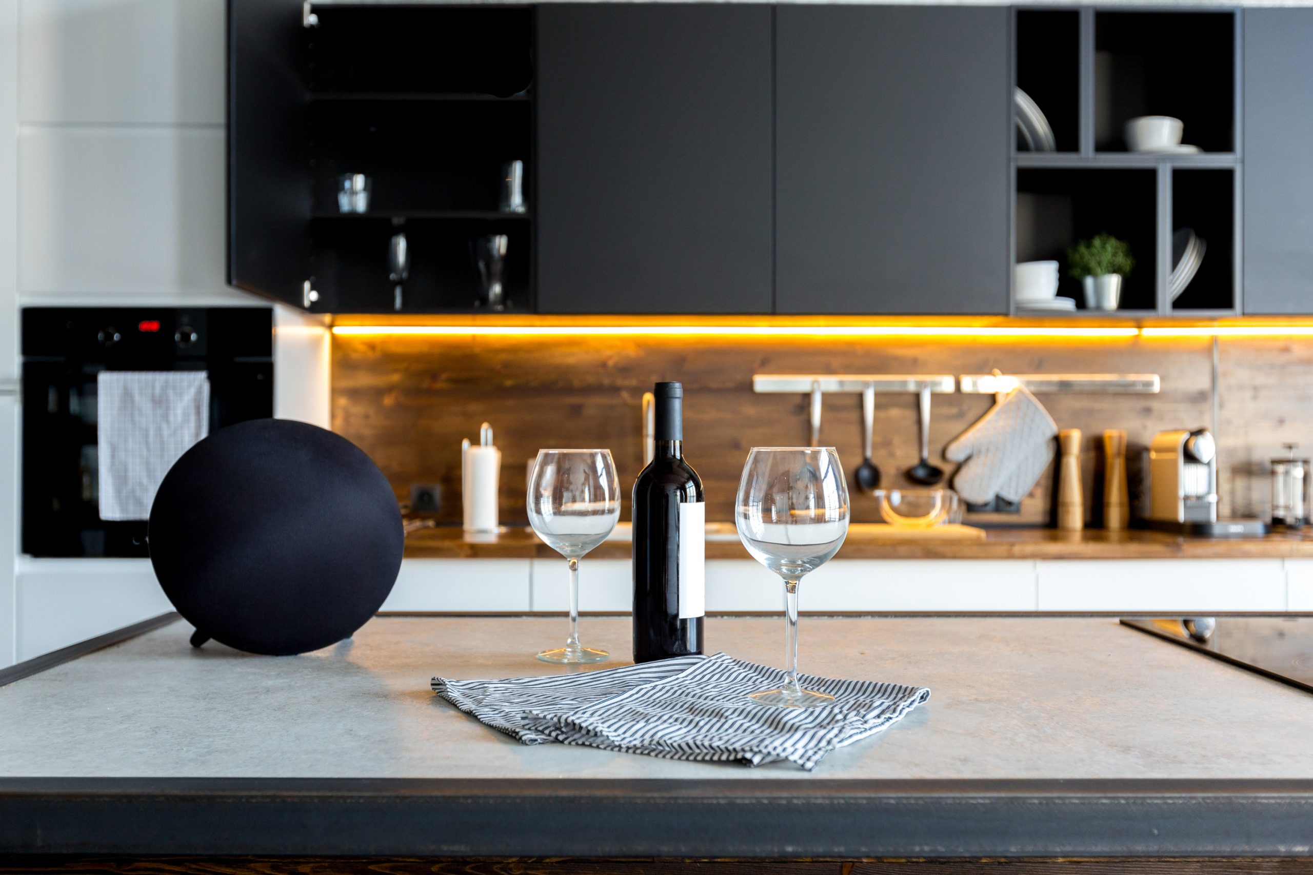 A kitchen counter with a wine glass and a bottle of wine.