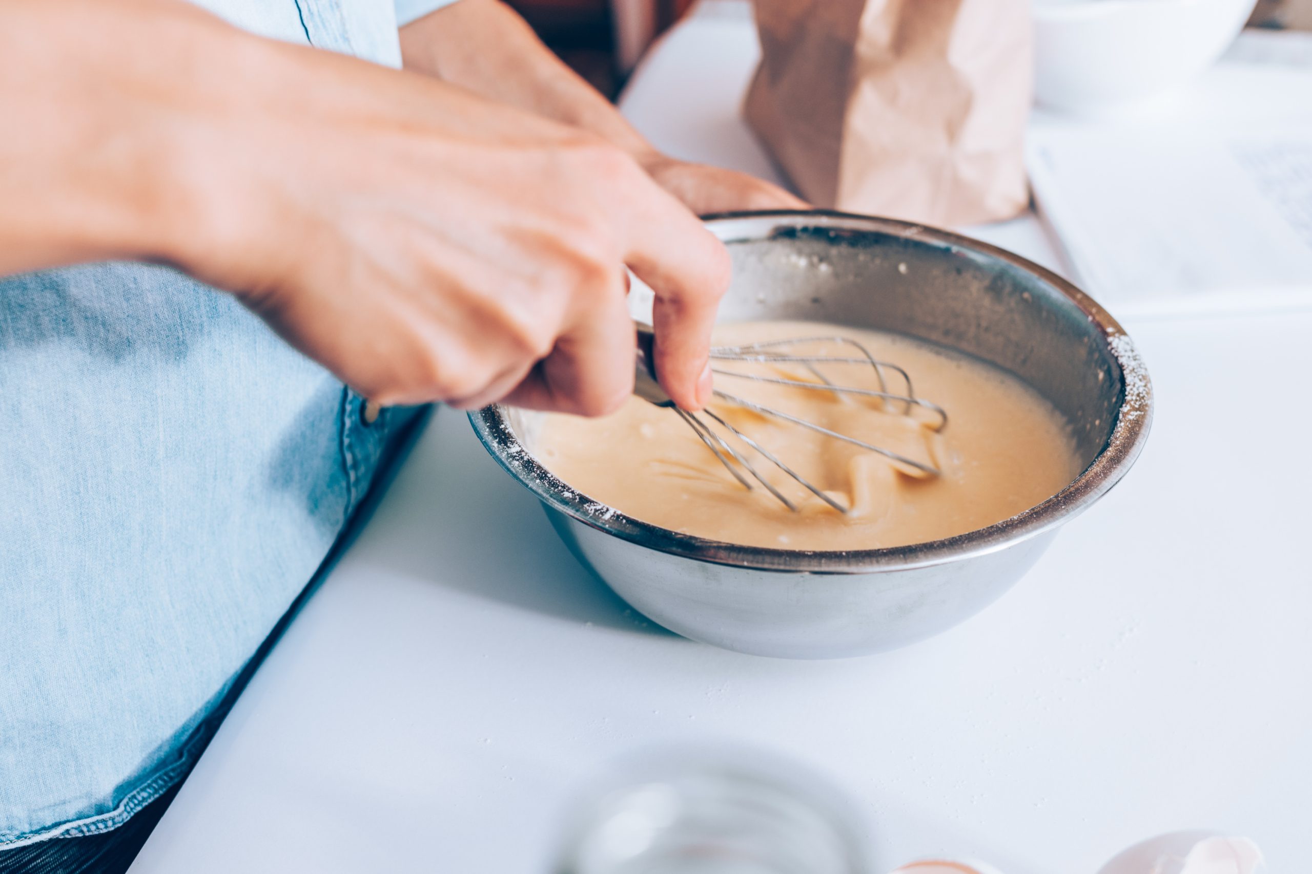 A woman is mixing eggs in a bowl while considering the difference between baking soda and baking powder.