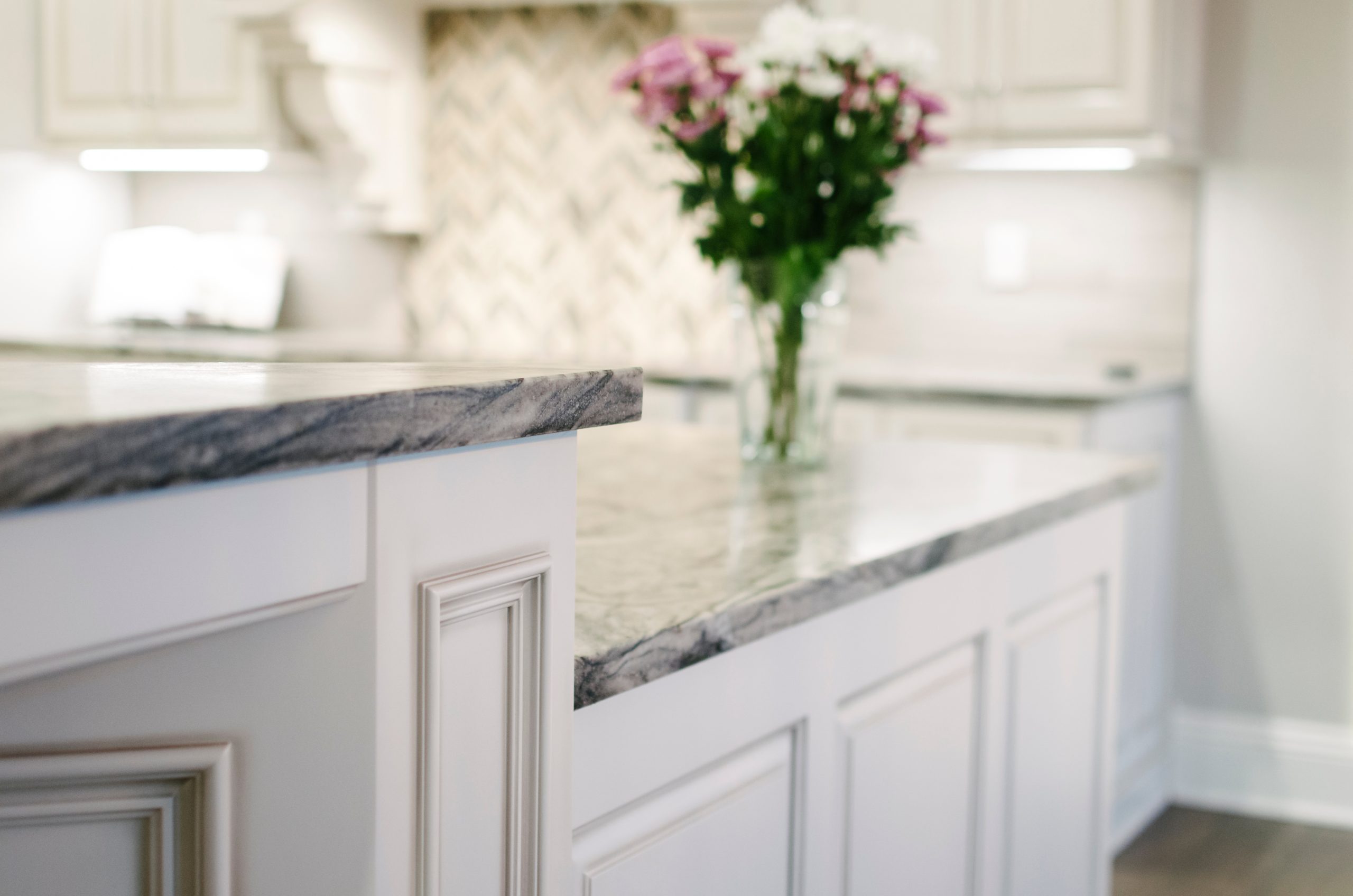A kitchen with marble counter tops and a vase of flowers.