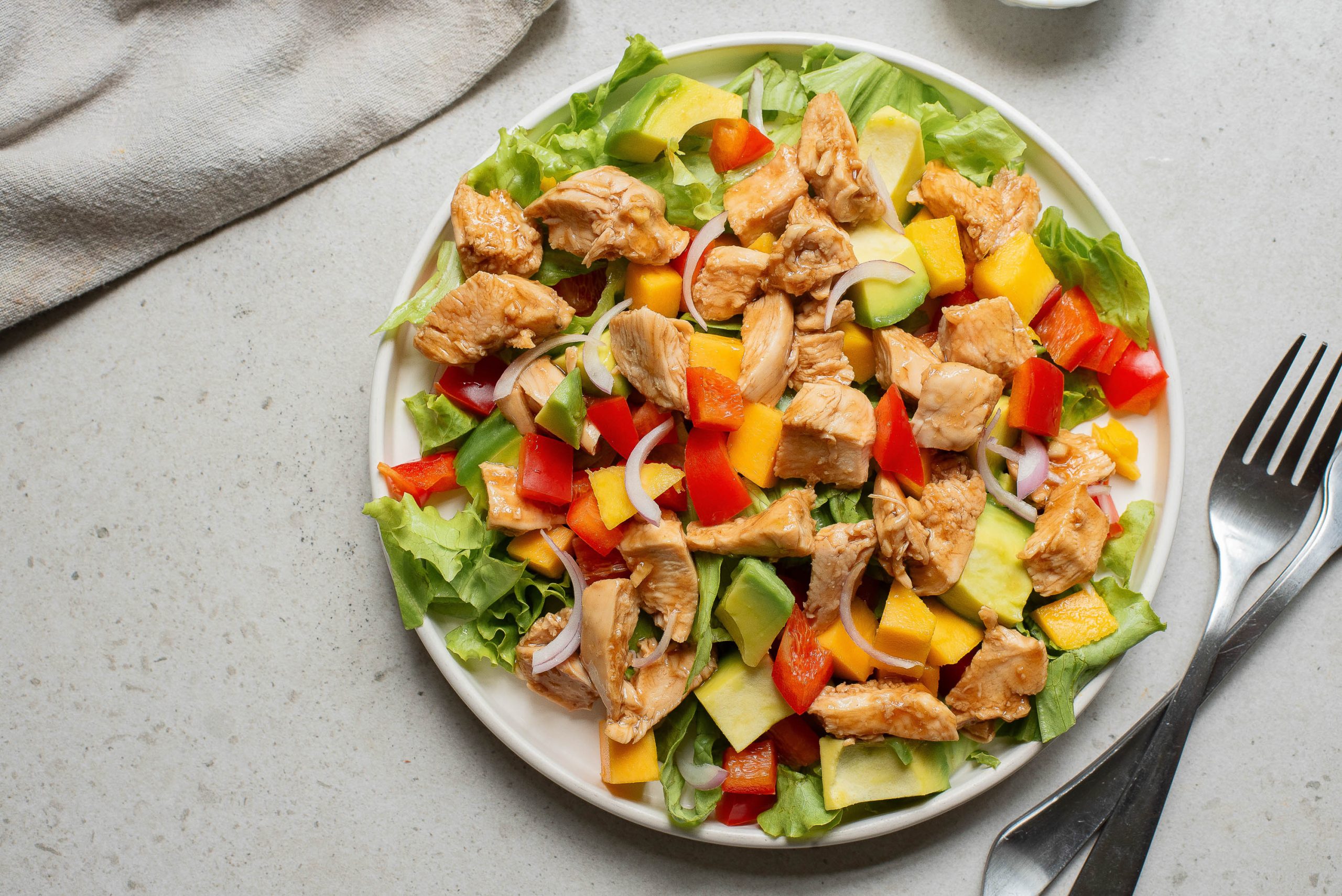 A plate of salad with chicken and vegetables.