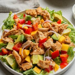 A plate of chicken salad with mango and avocado.