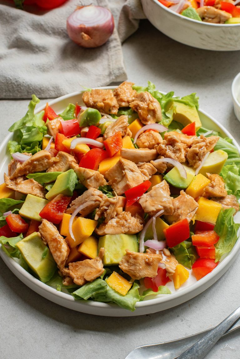 A plate of chicken salad with mango and avocado.