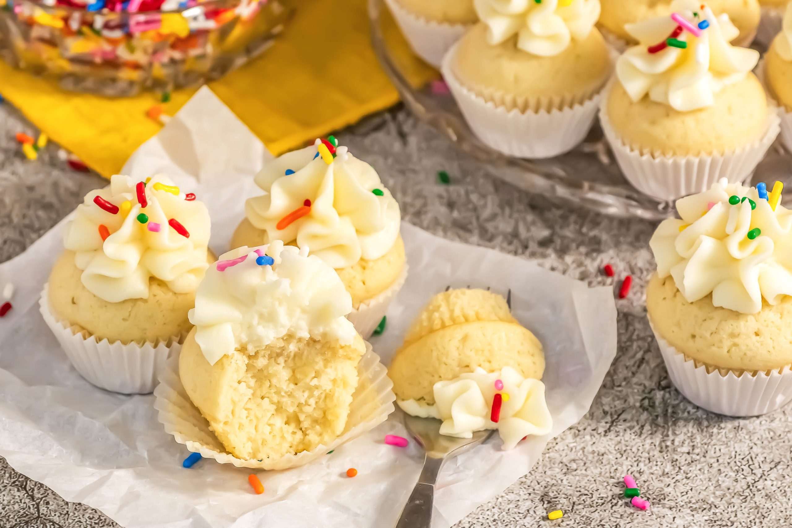 Cupcakes with sprinkles and a bite taken out of them.