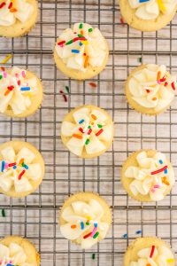 Cupcakes with sprinkles and frosting on a cooling rack.
