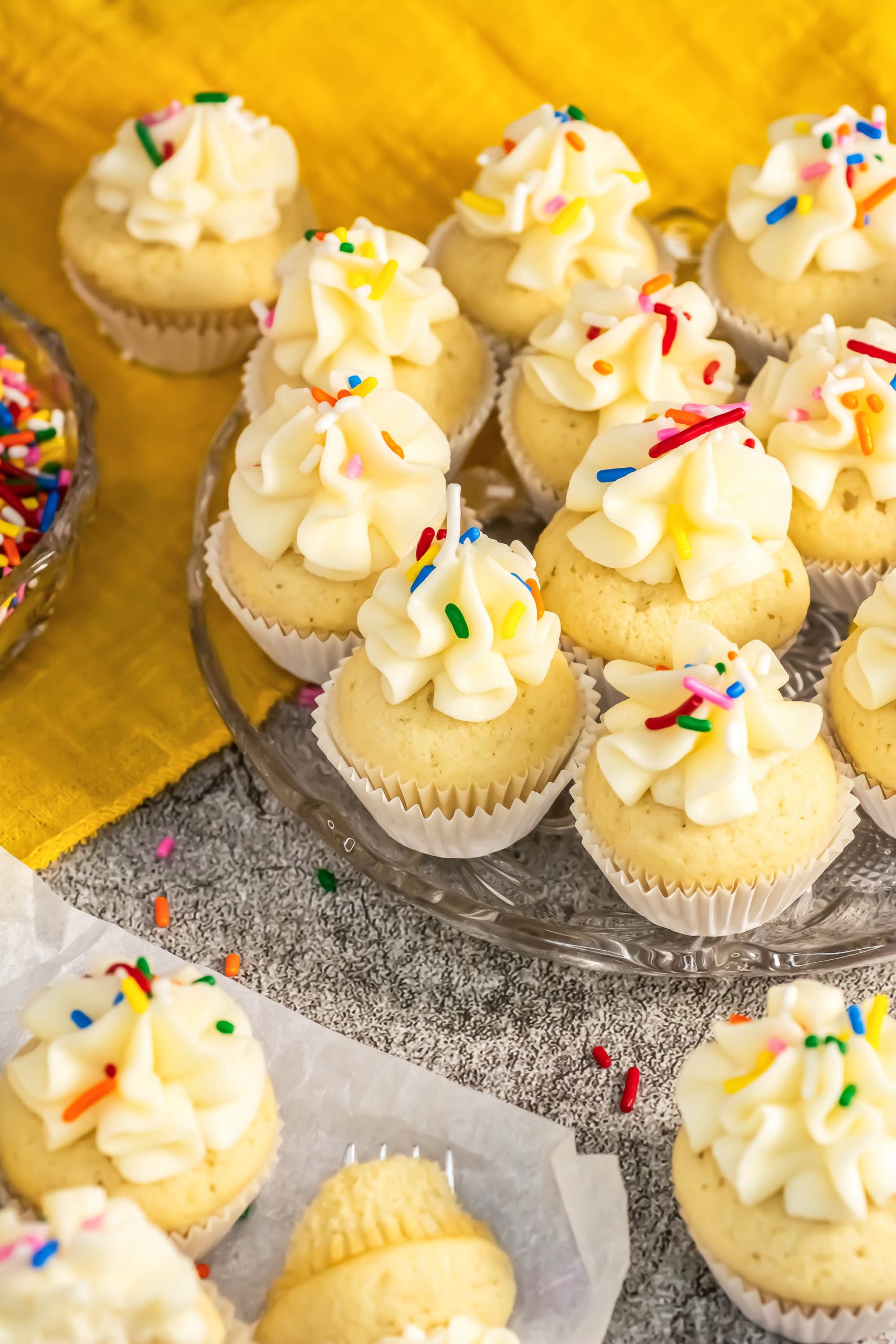 Classic Vanilla Cupcake with icing and sprinkles on a plate.