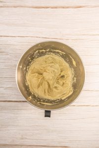 A bowl of yellow batter on a wooden table.