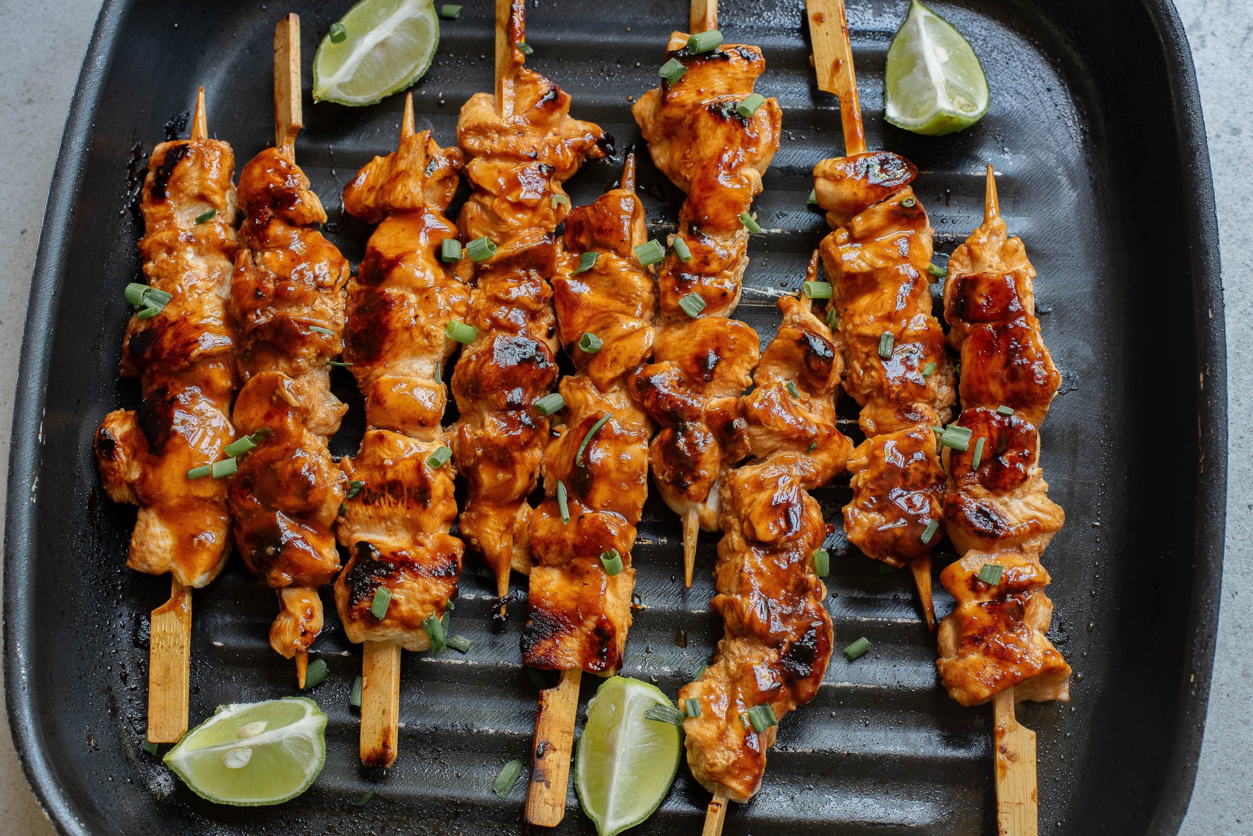 A plate of Honey Beer Chicken Kabobson a grill.