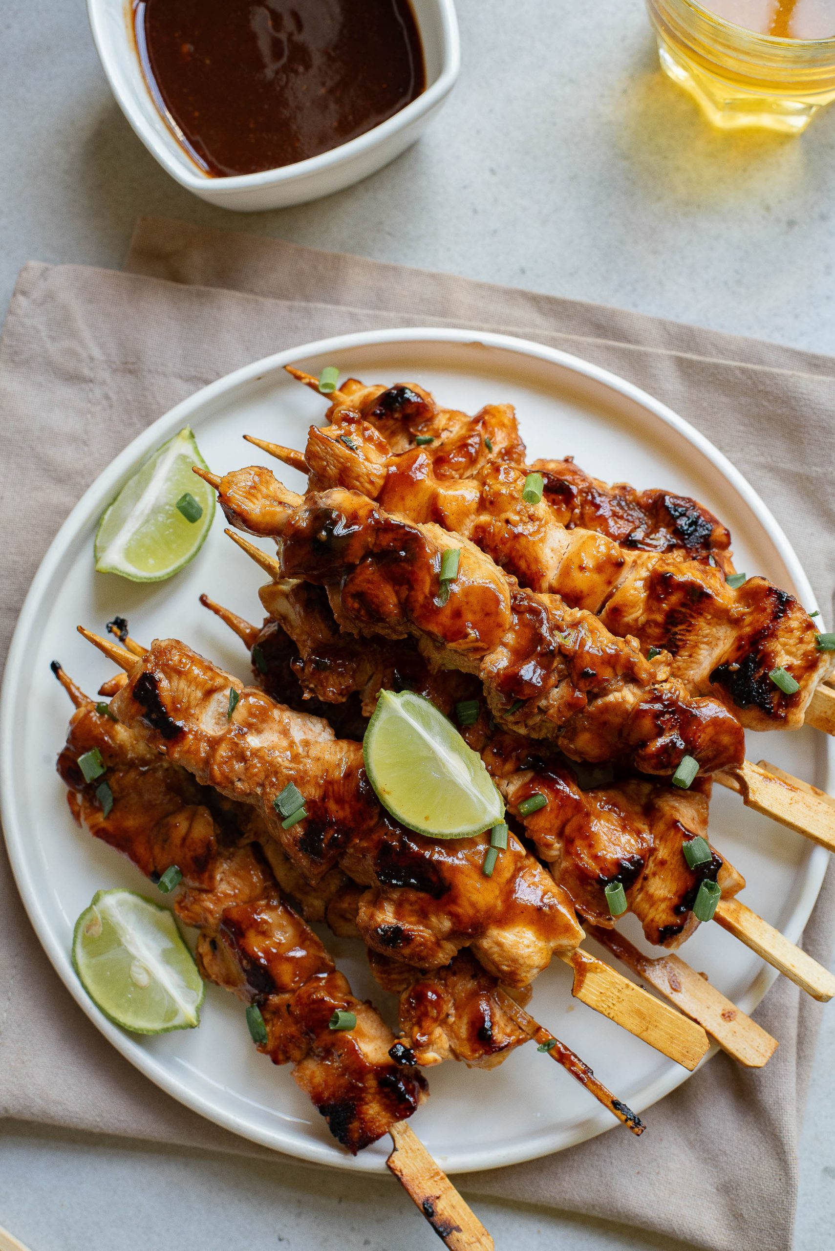 A plate of chicken skewers with lime slices on top.