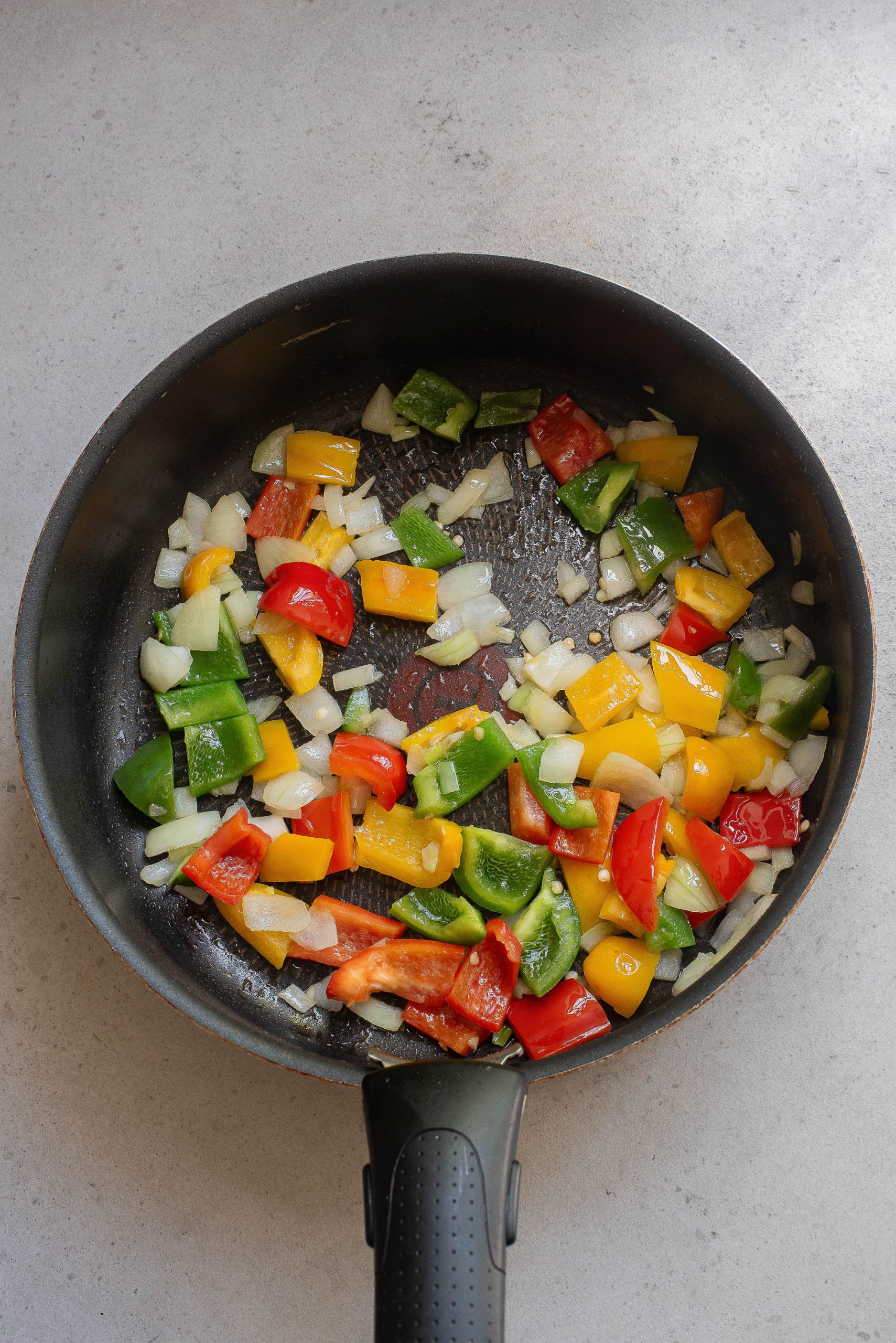 A frying pan with peppers and onions in it.
