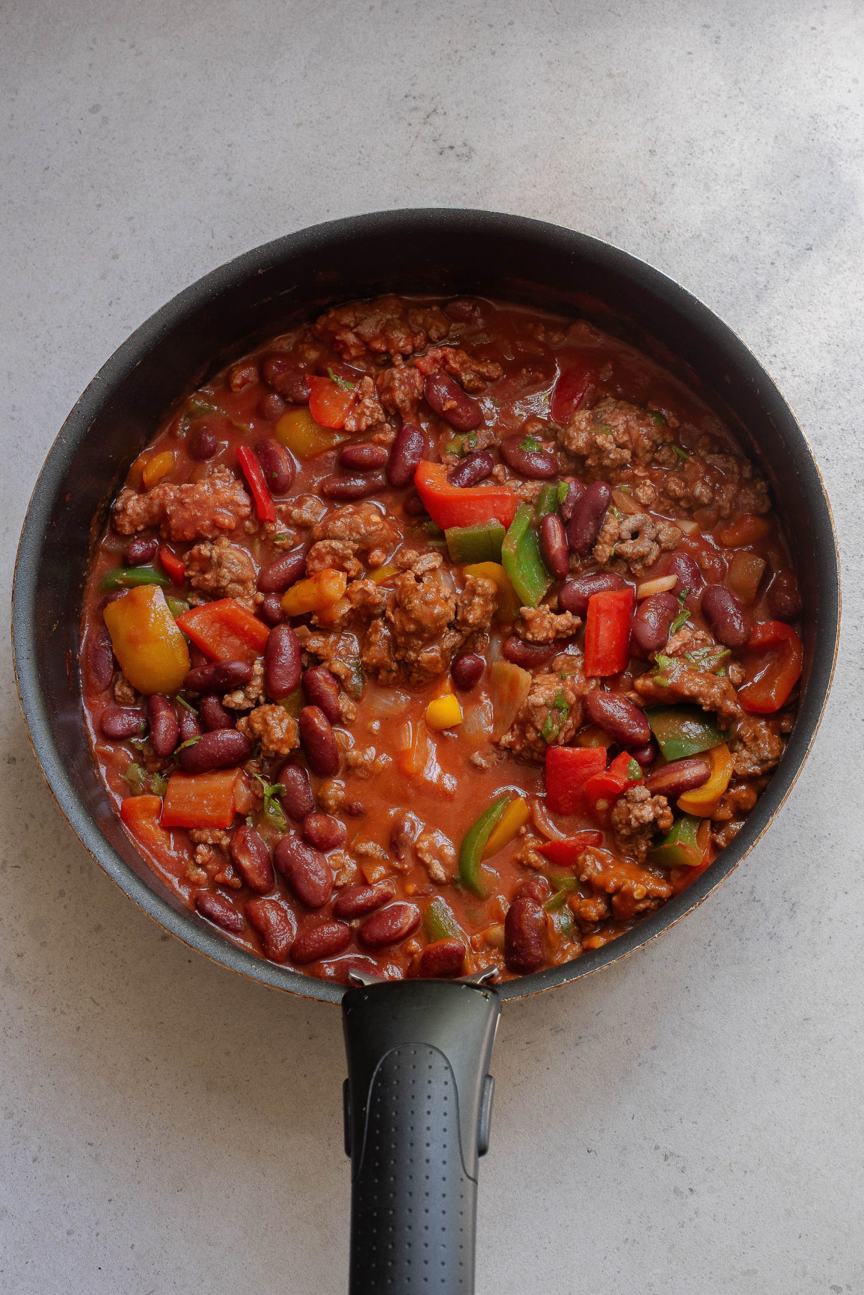 A frying pan filled with chili, beans and peppers.