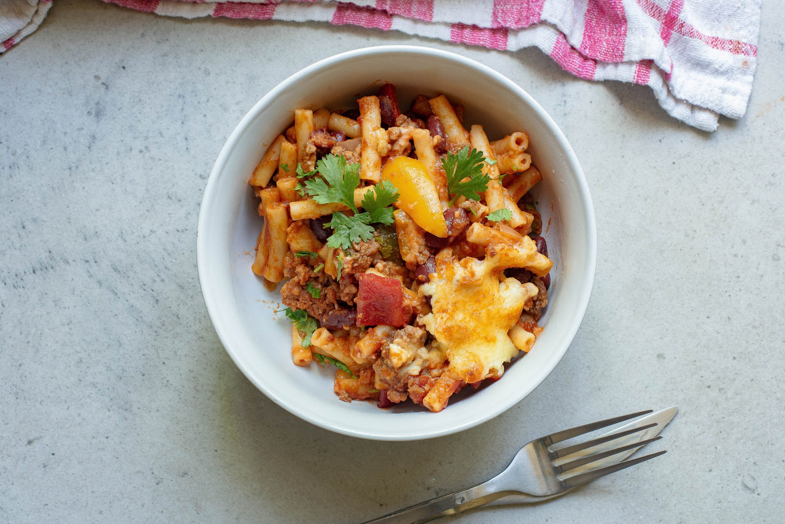 A bowl of pasta with meat and cheese in it.