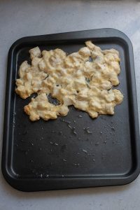 A black baking sheet with a piece of food on it.