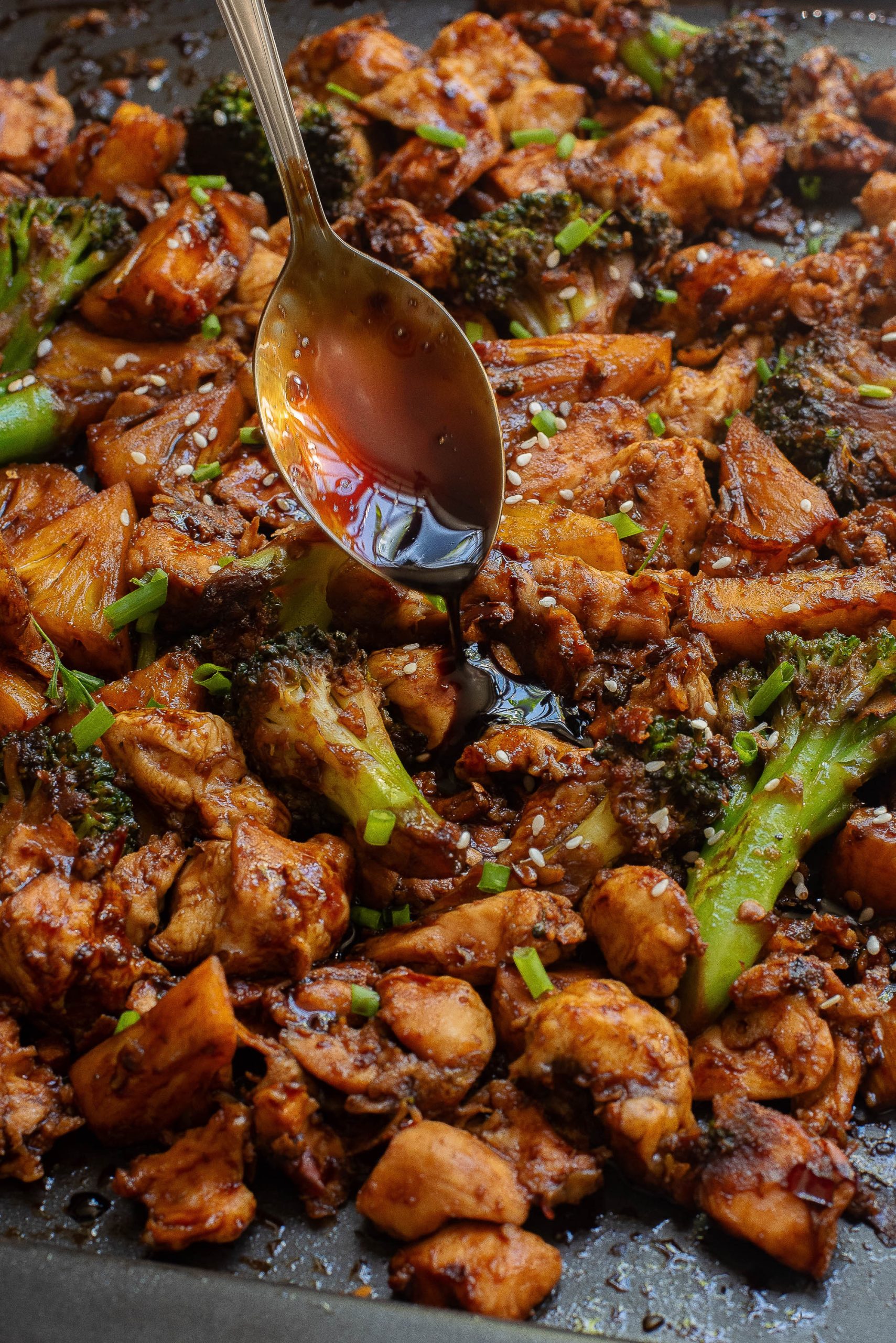 A spoon is being used to eat a dish of chicken and broccoli.