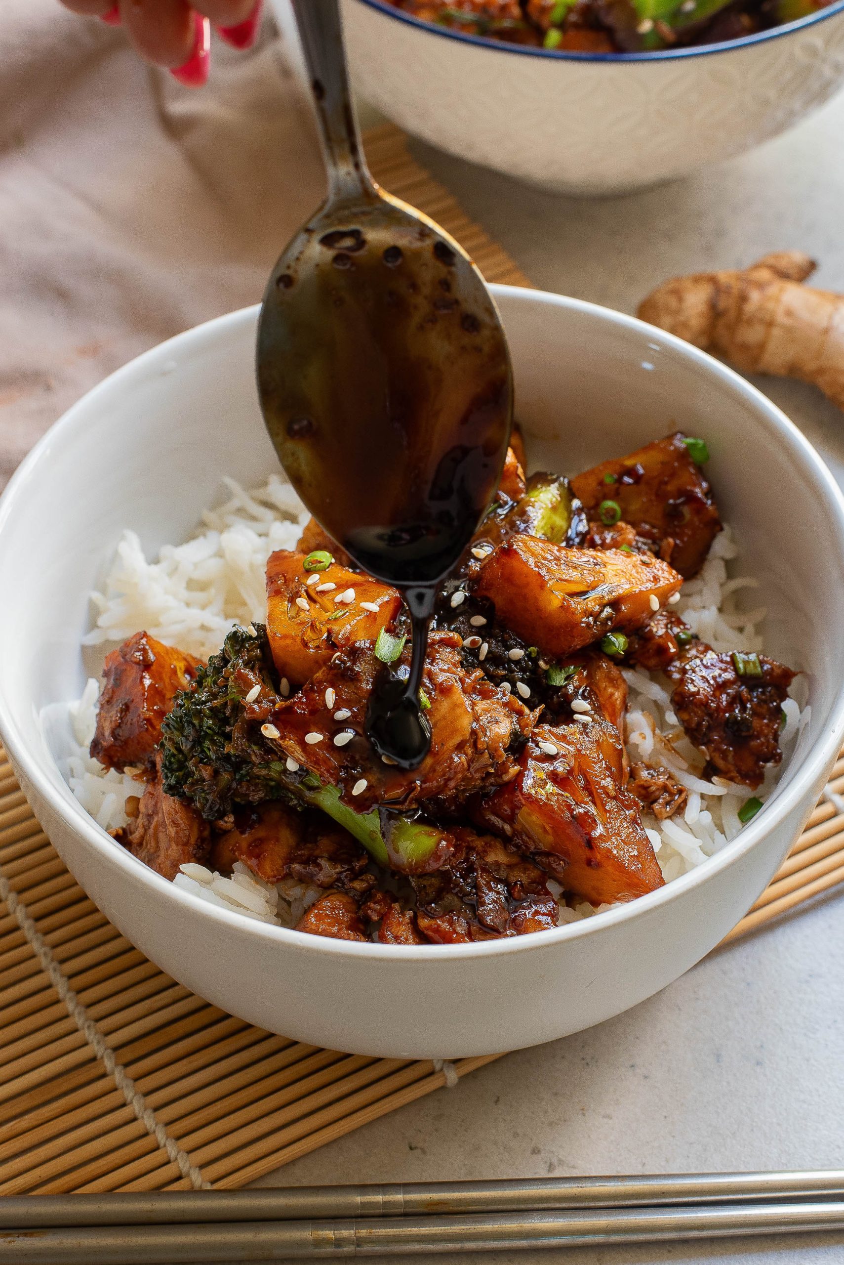 A bowl of asian food with a spoon in it.