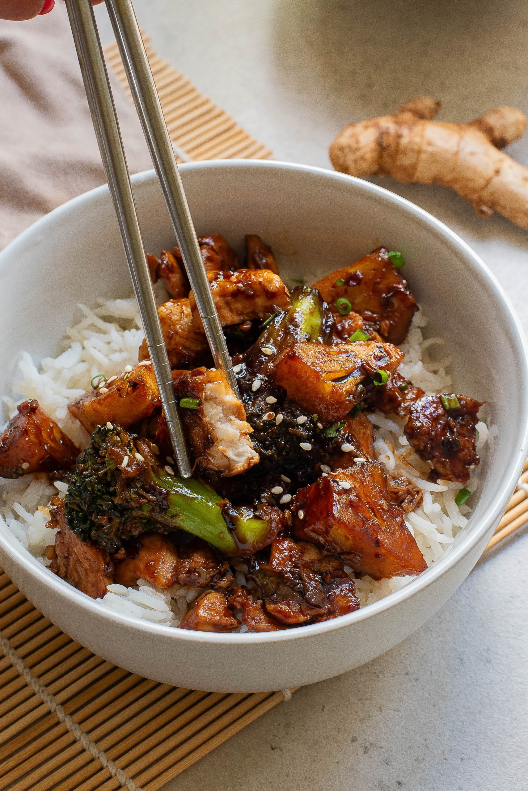 A person is holding chopsticks over a bowl of food.