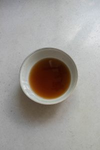 A bowl of brown sauce sitting on a table.