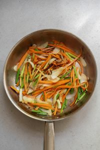 A frying pan filled with carrots and onions.