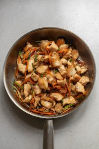 A frying pan filled with chicken and vegetables.