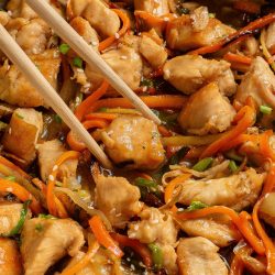 Chinese chicken stir fry in a pan with chopsticks.