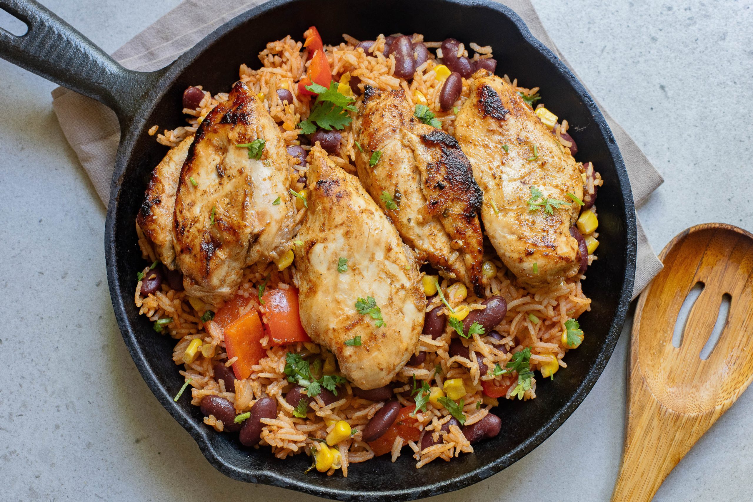 Ground Chicken Burrito Casserolein a skillet with a wooden spoon.