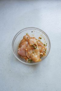 A bowl of chicken in a glass on a table.