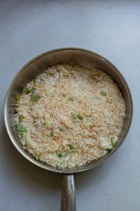 A frying pan filled with rice and vegetables.