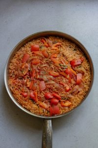 A pan full of rice and vegetables on a table.