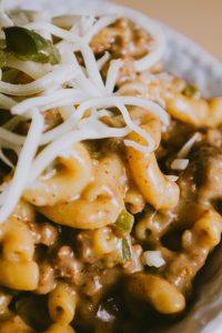 A bowl of macaroni and cheese with meat and cheese.