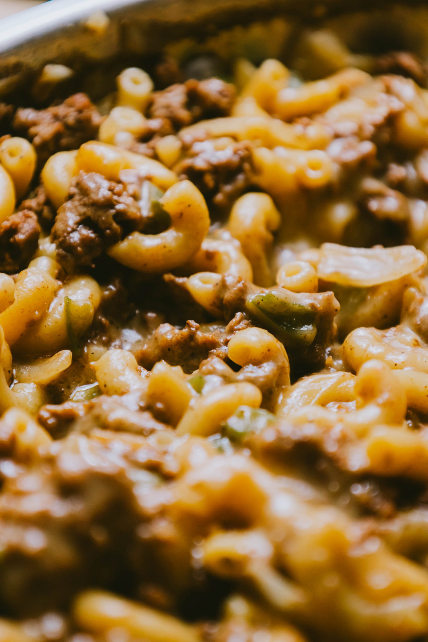 A close up of macaroni and cheese with beef and green beans.